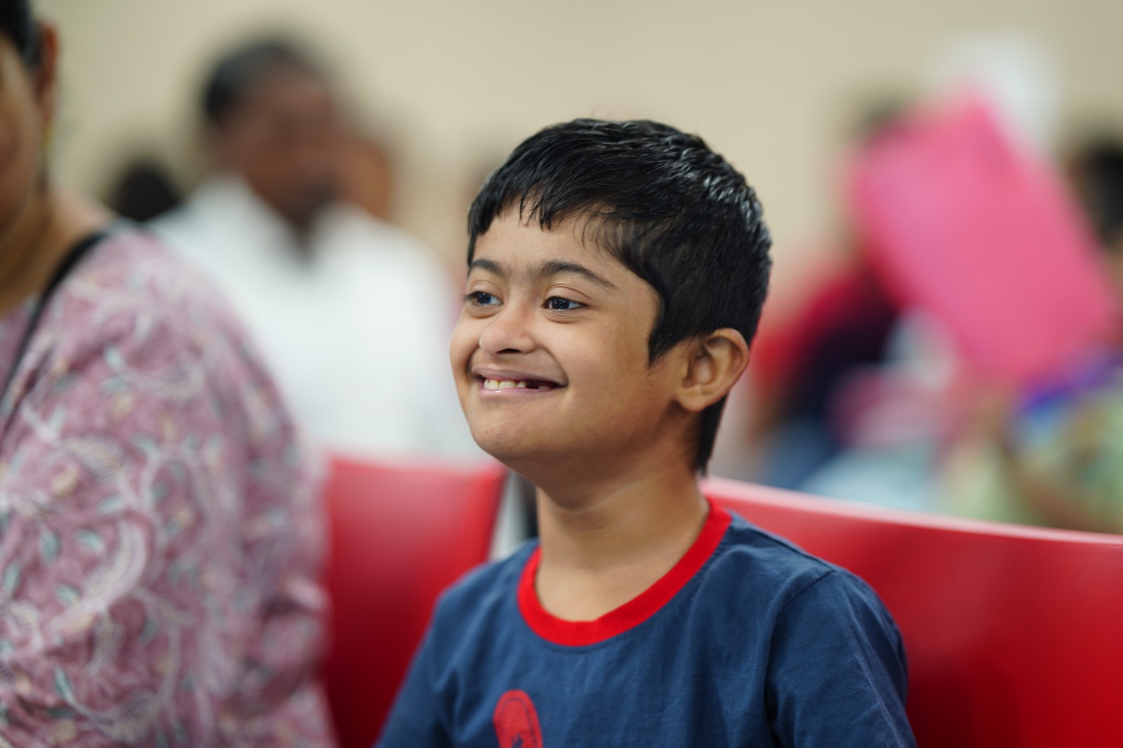 A smiling boy seated at a DigiAbility community event