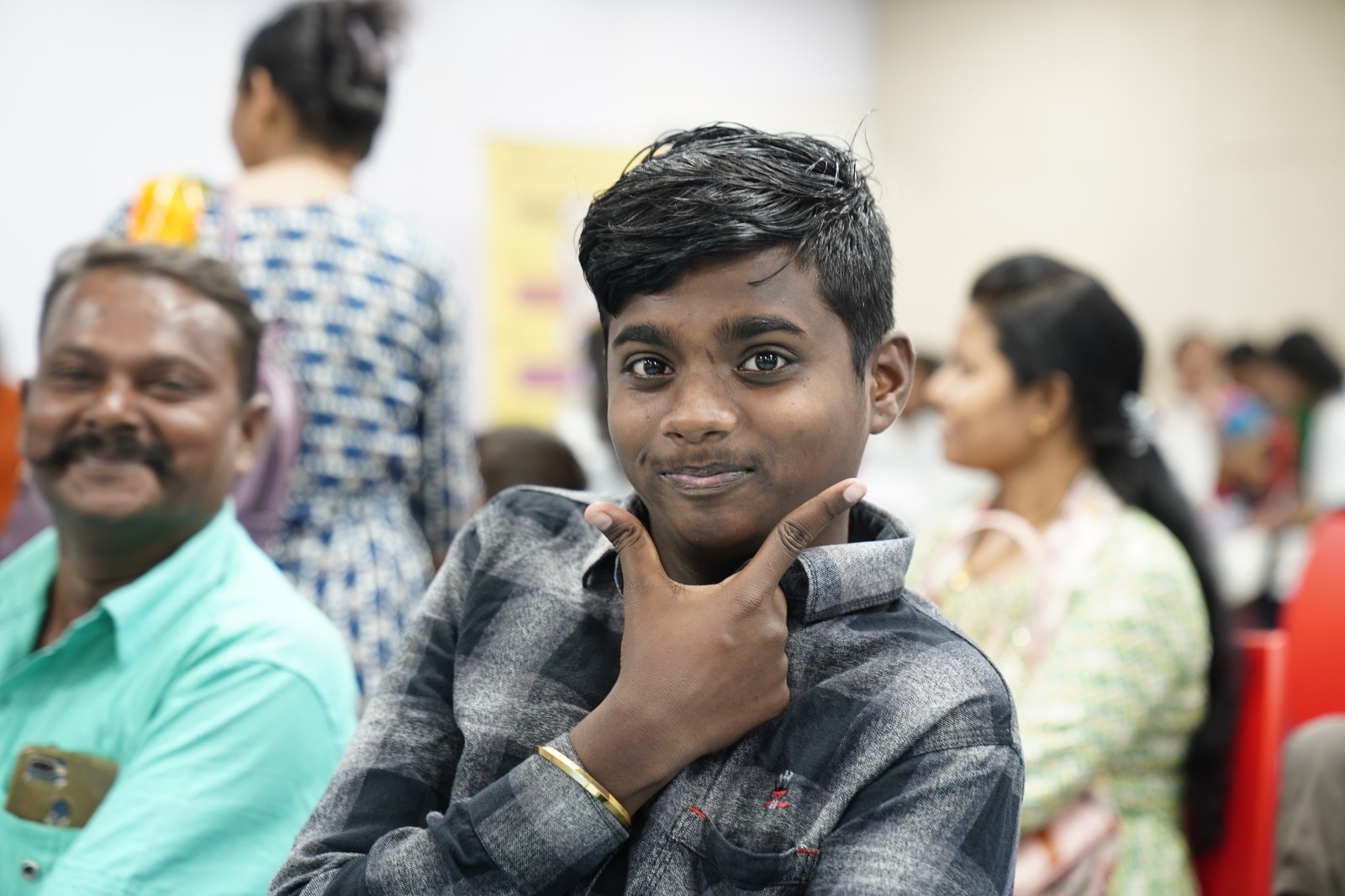 A smiling boy resting his chin on his hand at a DigiAbility community event